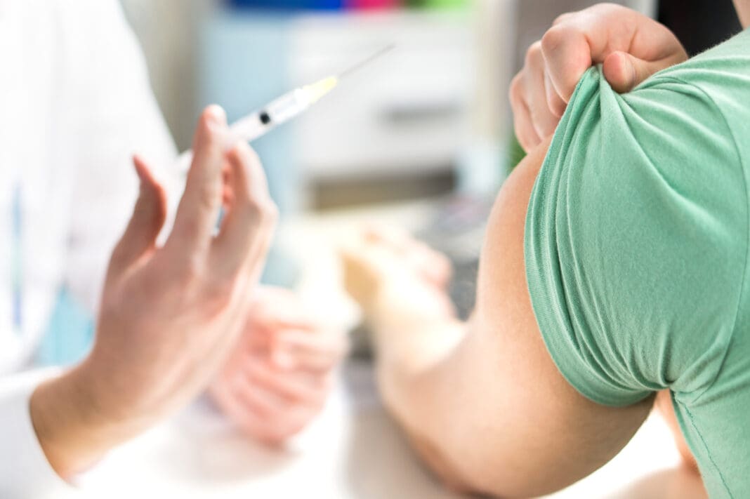 Doctor giving patient vaccine, flu or influenza shot or taking blood test with needle. Nurse with injection or syringe.